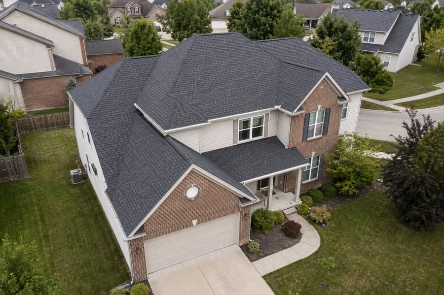 Aerial view of a two-story home with a charcoal architectural shingle roof