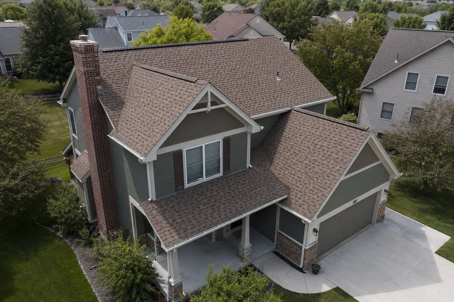 Aerial view of a two-story home with a weathered brown dimensional shingle multi-gable roof