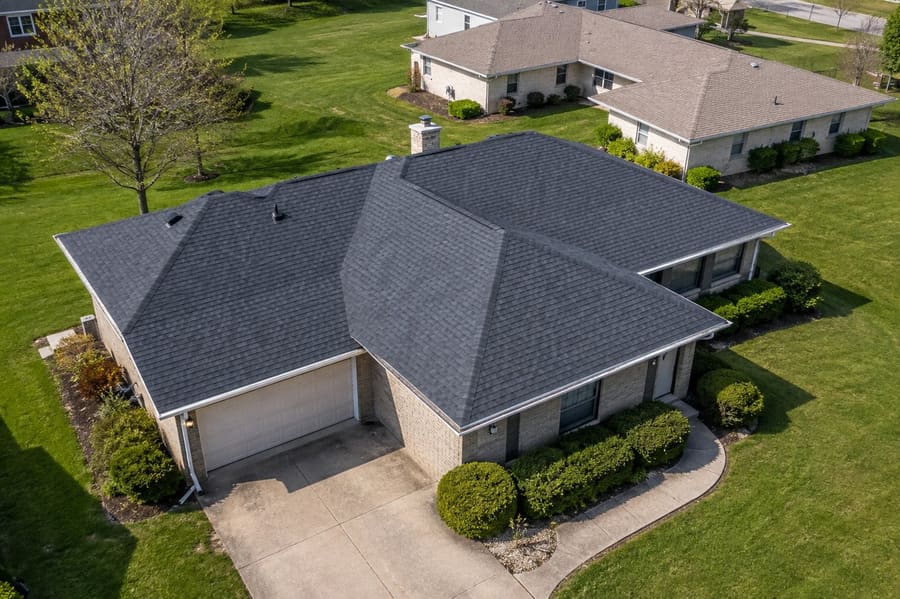 Aerial view of a brick ranch with a charcoal architectural shingle multi-hip roof